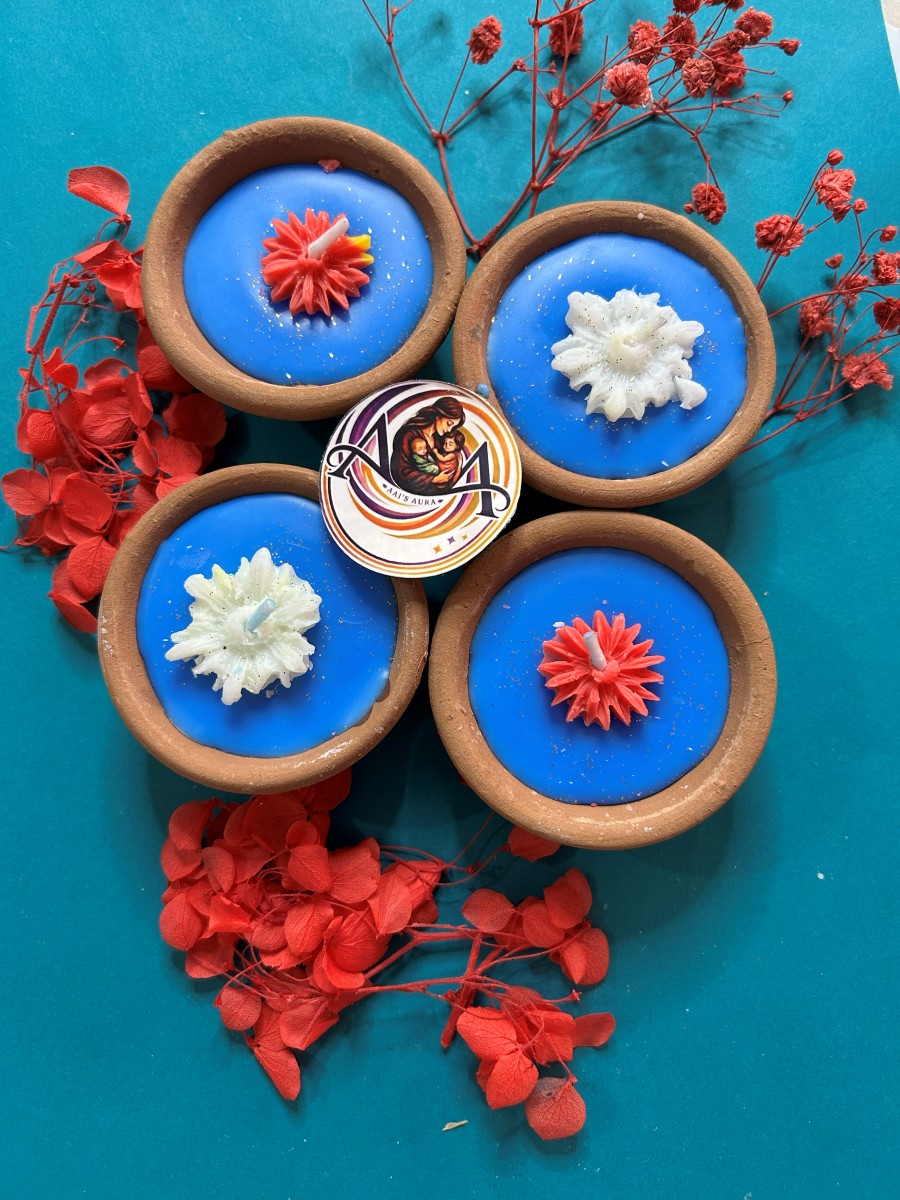 Four blue clay diya candles with red and white wax flowers