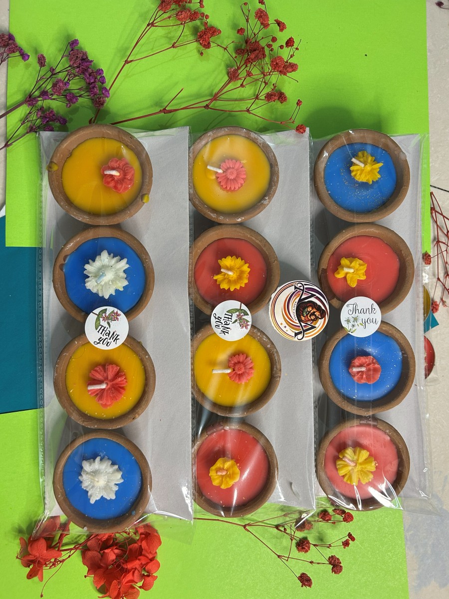 Several packed sets of blue, yellow, and red clay diya candles