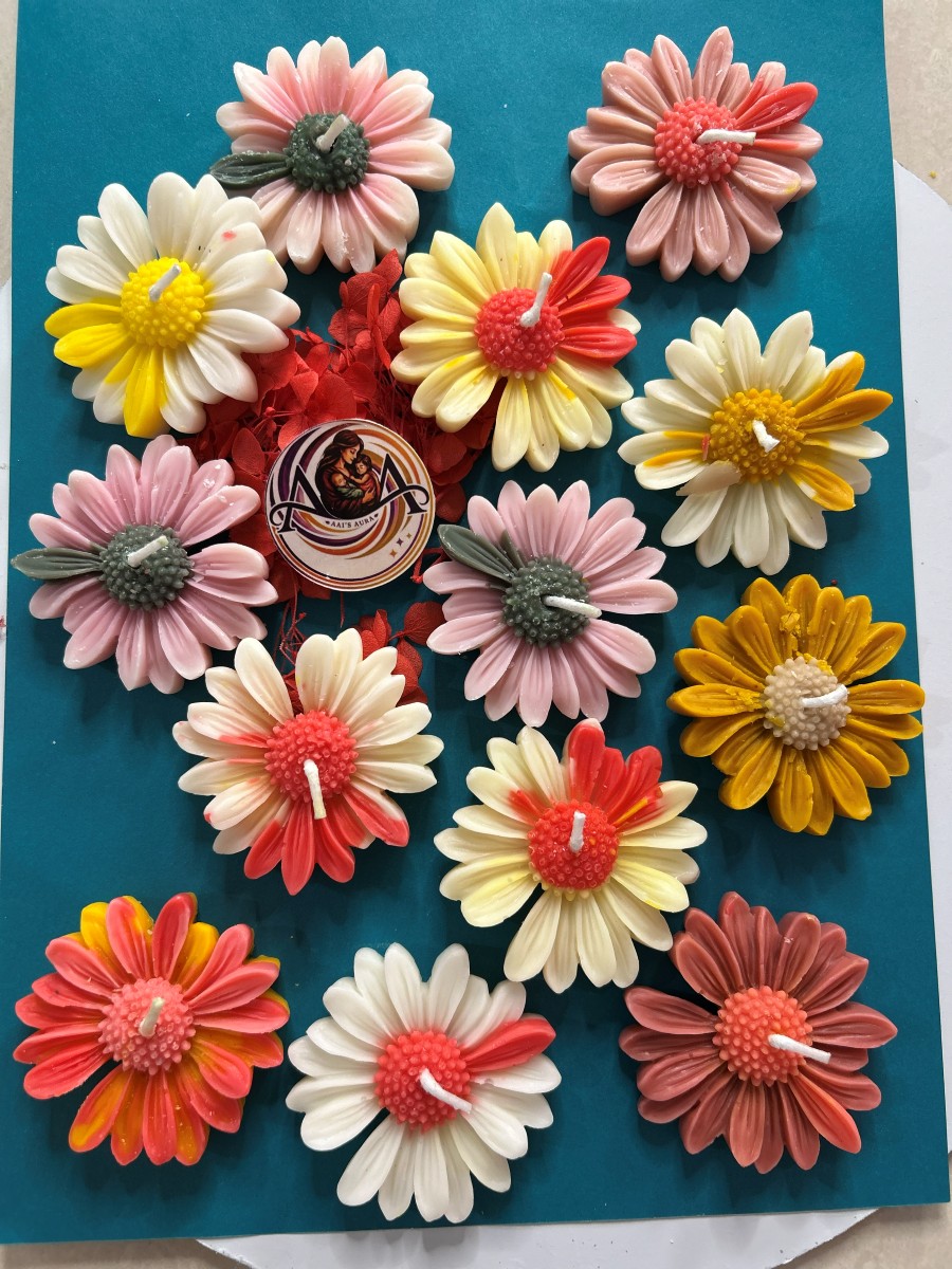A group of daisy candles in pink, coral, yellow, and white
