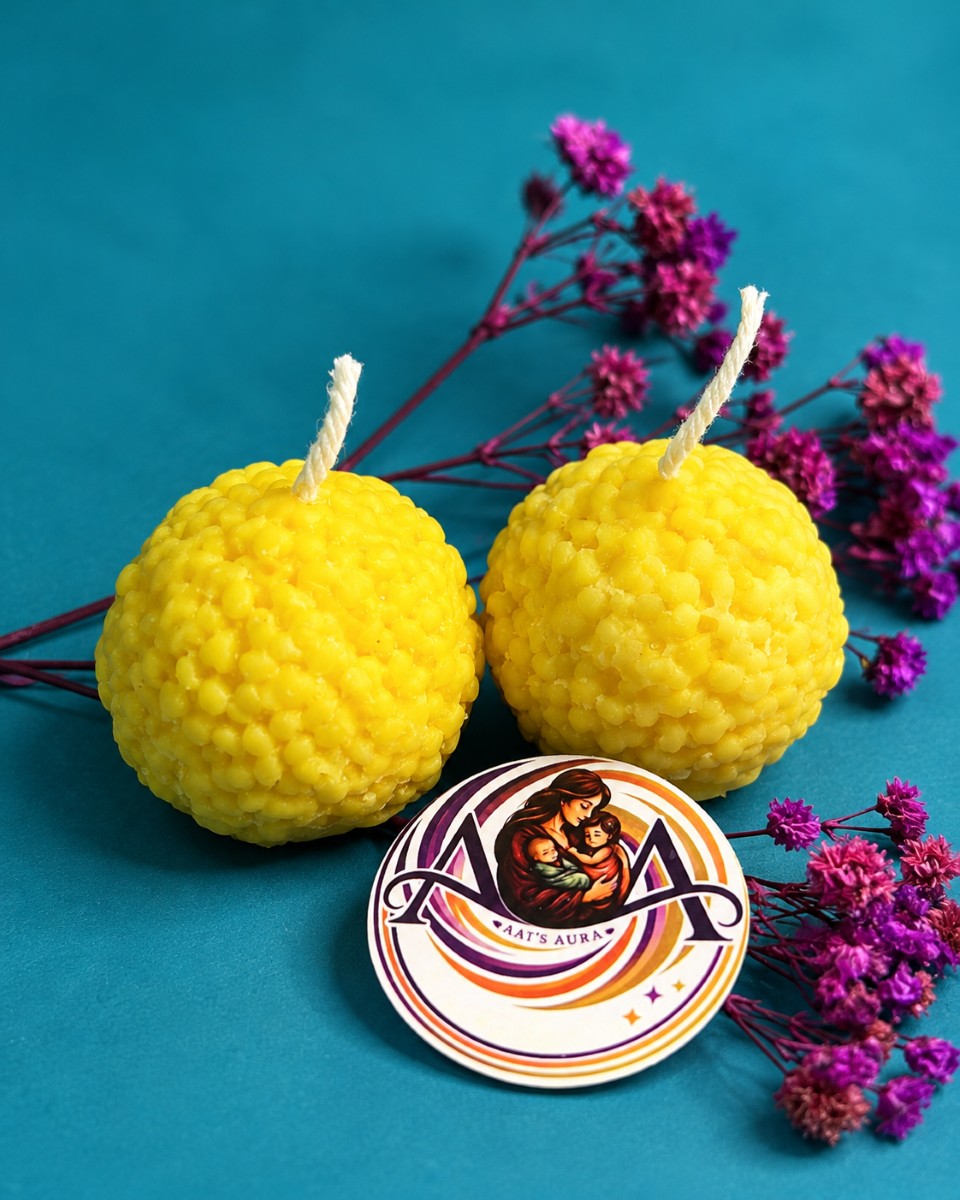 Two yellow textured laddu candles with the brand sticker