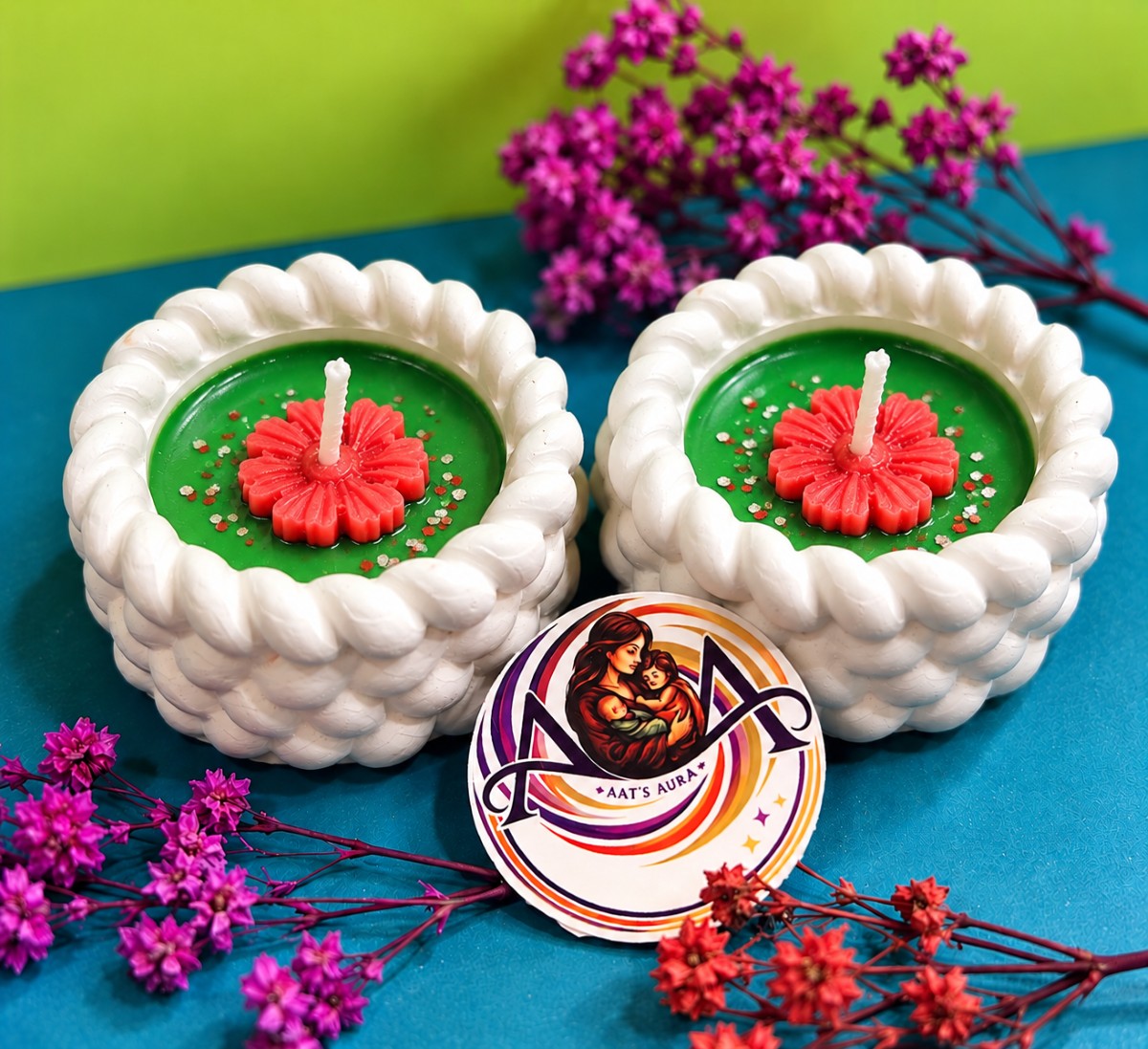 Two green marble diya candles with red wax flowers
