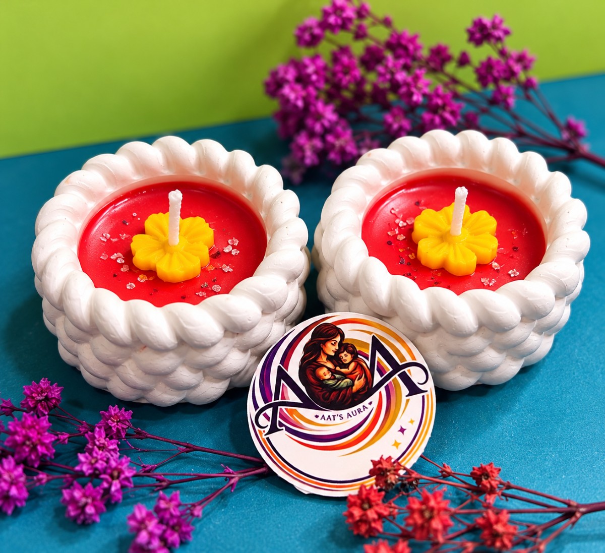 Two red marble diya candles with yellow wax flowers