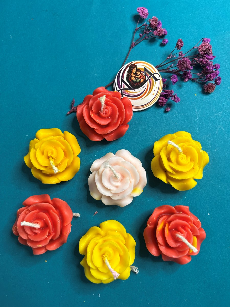 A pale pink rose candle among red and yellow roses