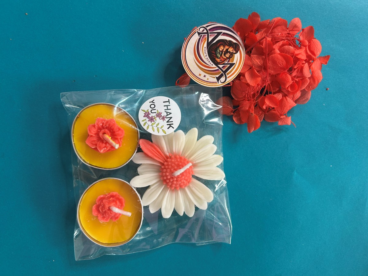 Two yellow tea lights and one white daisy candle in a clear pack